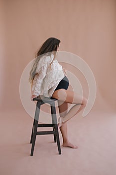 Pregnant woman with long hair in white sweater.