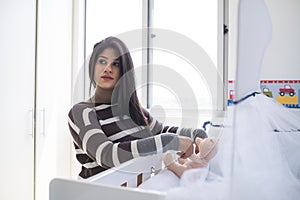 Pregnant woman looking at baby`s crib