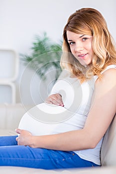 Pregnant woman looking at camera with hands on belly
