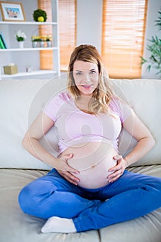 Pregnant woman looking at camera with hands on belly