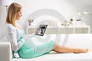 Pregnant woman looking at her babies first sonography results on tablet