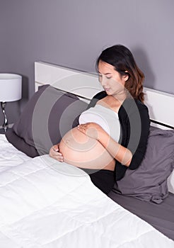 Pregnant woman looking at her belly while lying on bed