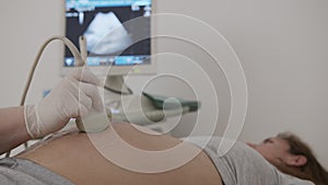 Pregnant woman looking at procedure ultrasound scan of baby. Examination of baby at ultrasound.