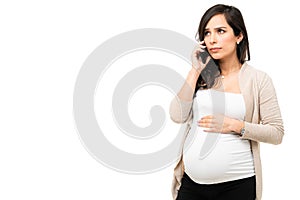 Pregnant woman looking scared while talking on the phone