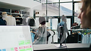 Pregnant woman looking at trendy merchandise on stand hangers