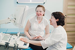 Pregnant woman looking at ultrasound shots of her growing baby showed by her doctor during medical examination