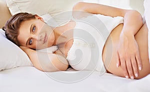 Pregnant woman, love stomach and portrait on bed with relax wellness and mindfulness for prenatal care. Person, smile