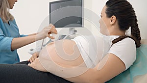 Pregnant woman lying at clinic during sonogram procedure