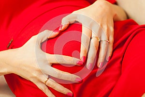 Pregnant woman makes heart shape over belly