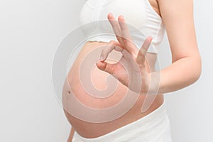 Pregnant woman making hand OK gesture with her belly