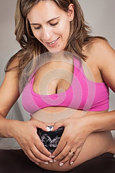 Pregnant Woman making a Heart over the Ultrasound