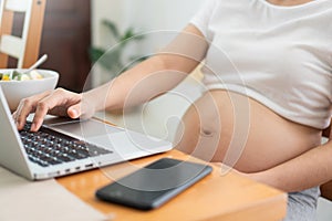 Pregnant Woman making online shopping on laptop at home