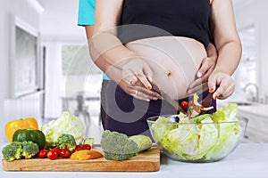 Pregnant woman making salad