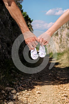 Pregnant woman and man holding baby shoes in hands. Future mom and dad, parents is holding little newborn baby shoes.