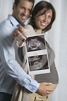 Pregnant Woman With Man Holding Out Sonogram