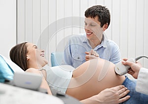 Pregnant woman and man on ultrasound exam in hospital.