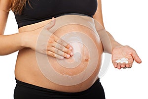 Pregnant woman massaging her belly with ointment against stretch