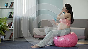 Pregnant woman massaging her body getting pleasure from special fitness balls