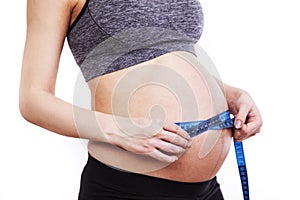 Pregnant woman measures her belly with a measure