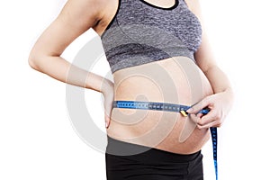 Pregnant woman measures her belly with a measure