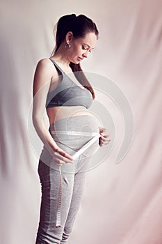 Pregnant woman measures her belly
