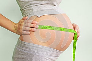 Pregnant woman measures her stomach. Pregnancy and weight gain. Pregnancy and sport. Big belly. Trimester