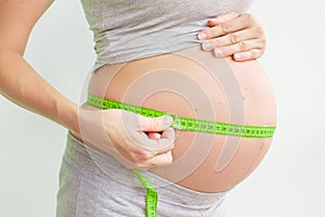 Pregnant woman measures her stomach. Pregnancy and weight gain. Pregnancy and sport. Big belly. Trimester