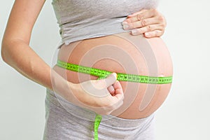 Pregnant woman measures her stomach. Pregnancy and weight gain. Pregnancy and sport. Big belly. Trimester