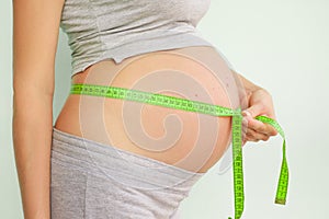 Pregnant woman measures her stomach. Pregnancy and weight gain. Pregnancy and sport. Big belly. Trimester