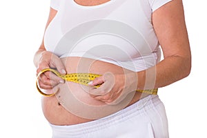 Pregnant woman measures her waist circumference with a tape measure photo