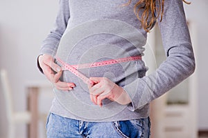 The pregnant woman measuring belly with centimeter