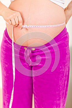 Pregnant woman measuring belly. Closeup.