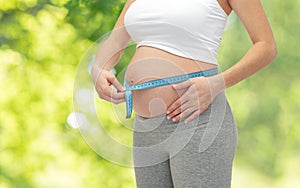 Pregnant woman measuring belly by tape measure