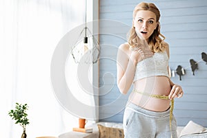 Pregnant woman measuring her tummy