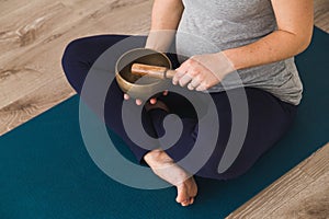 Pregnant woman meditating on yoga mat with a Tibetan singing bowl