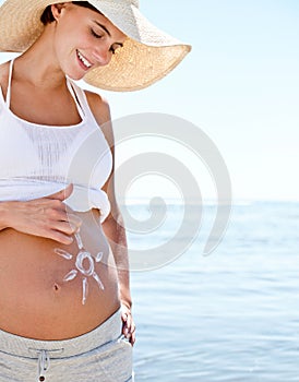 Pregnant woman, mom and sun drawing on belly with sunscreen, protection and summer at beach. Sea, travel and happy