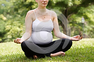 Pregnant woman mother belly relaxing park yoga lotus