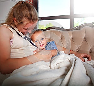 Pregnant woman mother and child playing at home on the bed