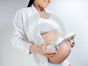 Pregnant woman music lover put the headphones on her belly to let Rebecca enjoy the music she likes. Girl waiting for a