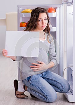 Pregnant woman near fridge with blank message