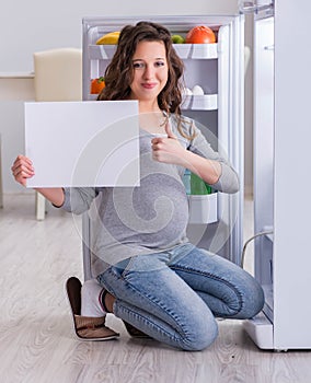 Pregnant woman near fridge with blank message