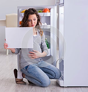 Pregnant woman near fridge with blank message