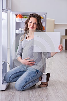 The pregnant woman near fridge with blank message