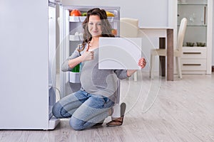 The pregnant woman near fridge with blank message