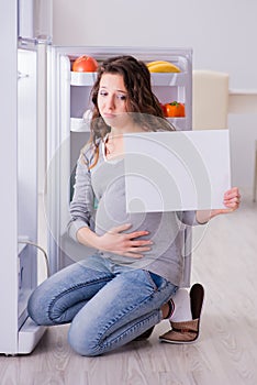 The pregnant woman near fridge with blank message