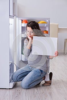 The pregnant woman near fridge with blank message