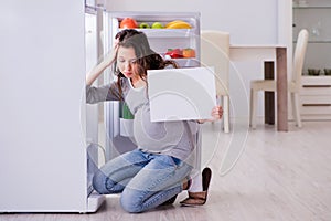 The pregnant woman near fridge with blank message