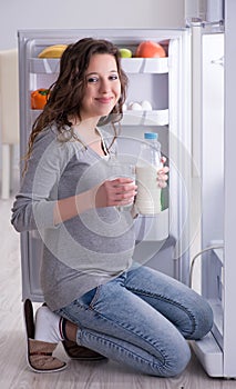 Pregnant woman near fridge looking for food and snacks