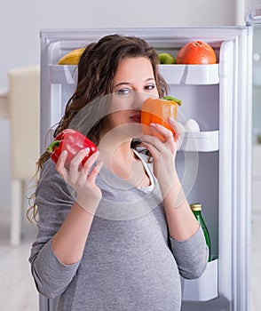 Pregnant woman near fridge looking for food and snacks