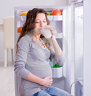 Pregnant woman near fridge looking for food and snacks